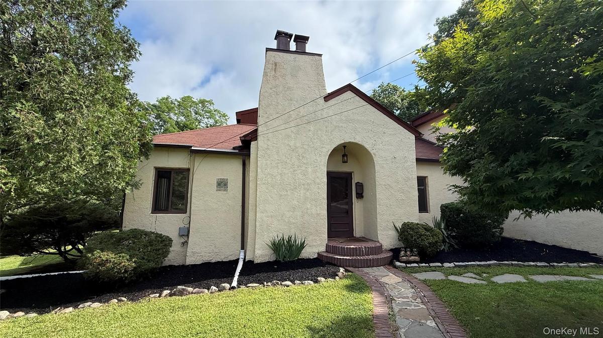 Stucco exterior with a prominent chimney and arched entry