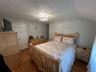 Hardwood flooring, overhead ceiling light fixture, white interior door, light-toned walls, and sloped ceiling detail