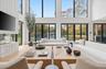 Living area featuring a towering ceiling, plenty of natural light, and wood finished floors