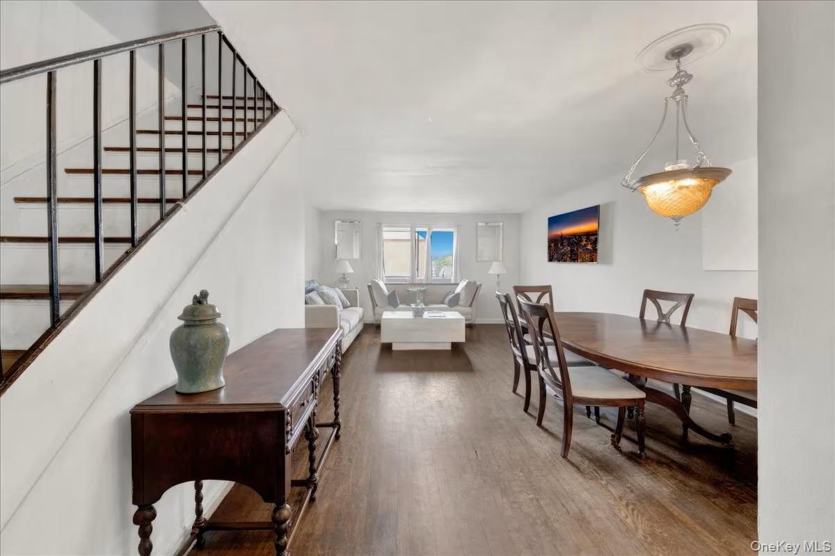 Open-concept living and dining areas featuring wood-finish flooring, a contemporary chandelier with ceiling medallion, and multiple windows providing