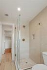 Bathroom featuring a shower stall, light wood-style flooring, a spacious closet, and recessed lighting