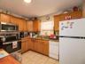 Kitchen featuring appliances with stainless steel finishes, light stone countertops, light tile patterned floors, and brown cabinets