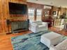 Living area with wood finished floors, wooden walls, and an AC wall unit