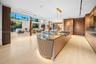 Designer kitchen with curved fluted island, book-matched stone countertop, gas cooktop, brass linear pendant, full-height walnut cabinetry, dramatic s