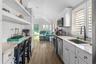 Kitchen with light stone counters, appliances with stainless steel finishes, vaulted ceiling, and sink