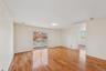 Spacious living area featuring wood-finish flooring, light neutral walls, and a large sliding glass door with a balcony