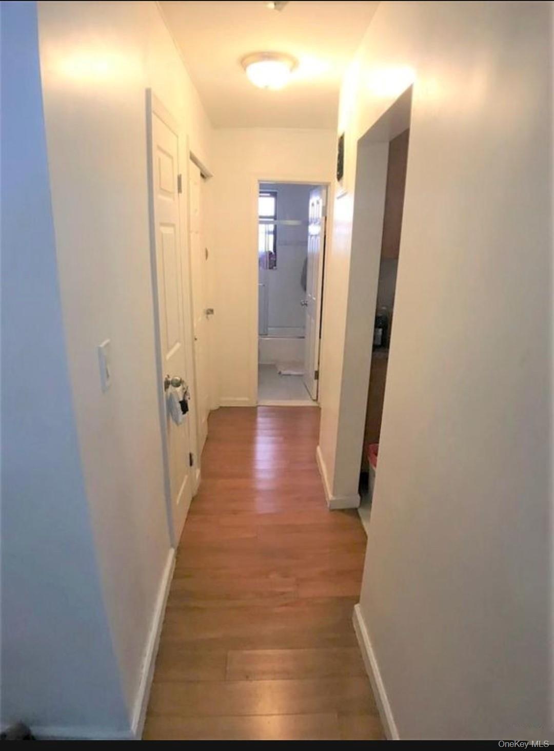 Corridor with light wood-type flooring and baseboards
