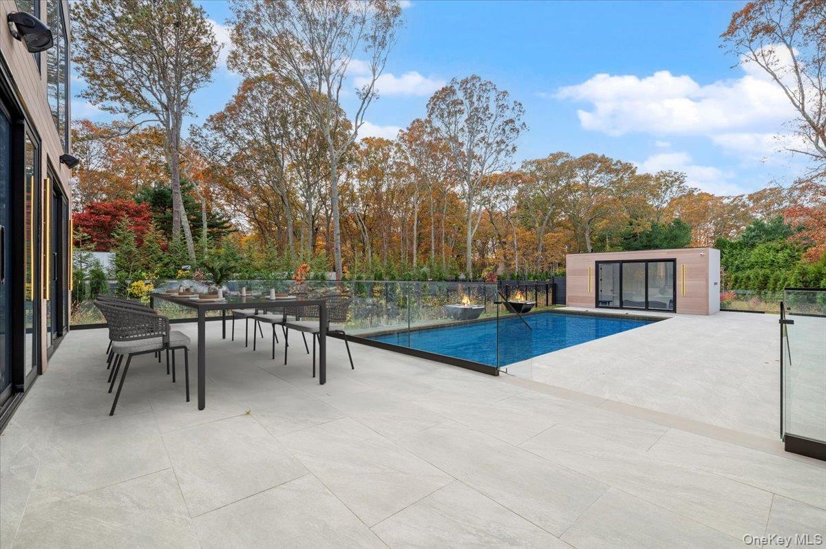 View of pool featuring a patio, outdoor dining space, and view of wooded area