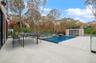 View of pool featuring a patio, outdoor dining space, and view of wooded area