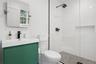 Bathroom with tiled shower, vanity, and toilet