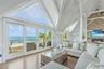 Living area featuring beamed ceiling, a water view, a fireplace, wood finished floors, and high vaulted ceiling