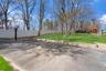 Paved court area with a basketball hoop, retaining wall, and a sloped lawn