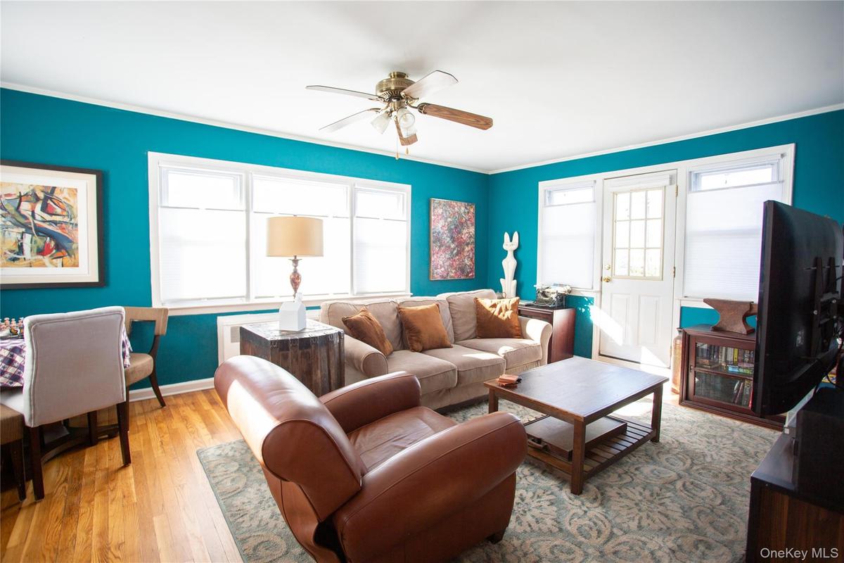 Living room featuring light wood-style floors, a ceiling fan, and crown molding
