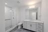 3rd bathroom Ensuite: The single vanity features shaker-style cabinetry with brushed nickel hardware, a sleek quartz countertop, and an oversized mirr