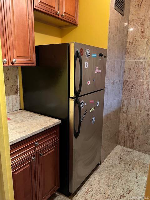 Kitchen with light stone counters and stainless steel refrigerator