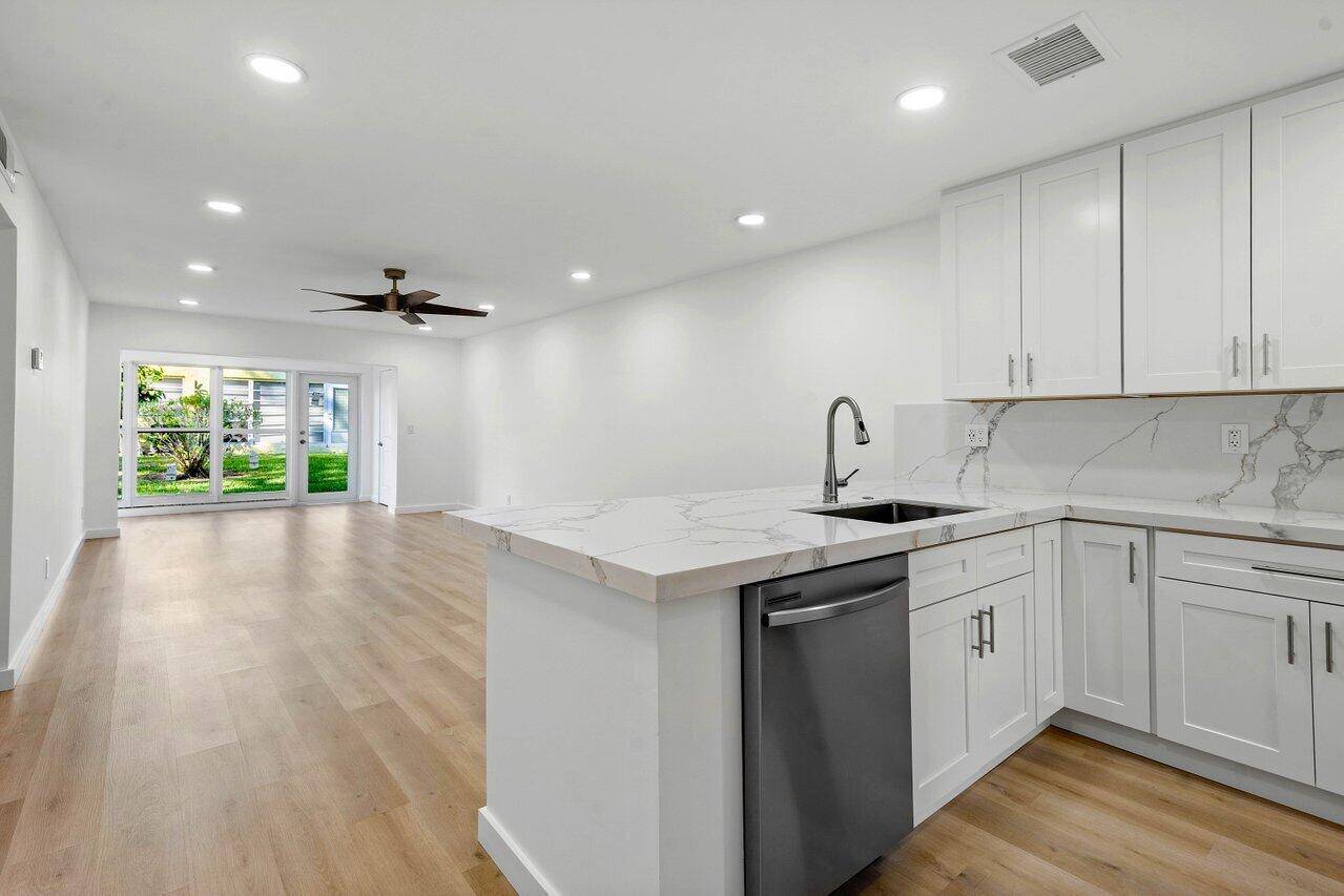 Exquisitely renovated, this luminous first floor corner condominium boasts all IMPACT GLASS windows and doors, two bedrooms and two full baths, within the esteemed 55 enclave of Pines of Delray.