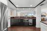 Custom bar area provides ample storage, a wine refridgerator, extra bottle storage and microwave.