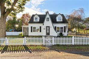 A touch of visual elegance this pretty Cape Cod home has a classic white fence and an architecturally pleasing exterior entrance.