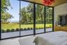 First floor primary bedroom with floor to ceiling windows, access to outdoor terrace, large walk-in closet and en suite bath.