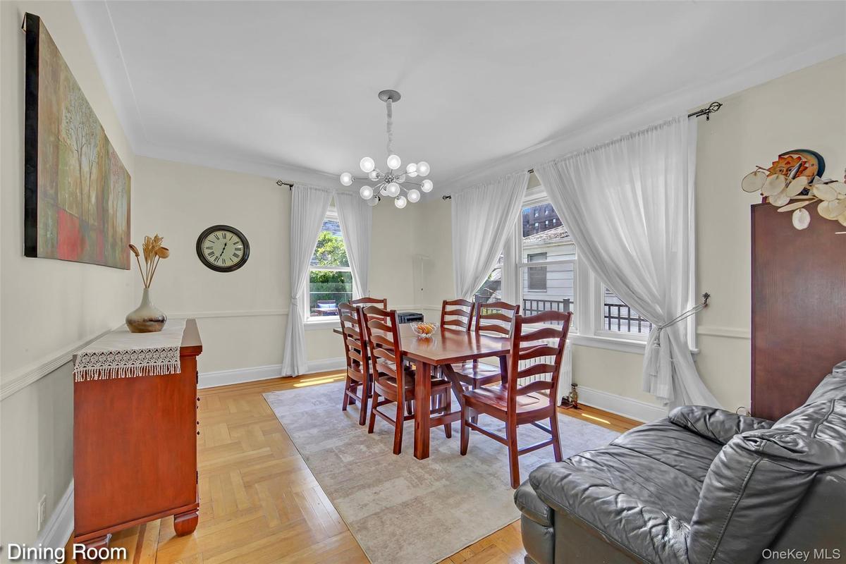 Dining area featuring herringbone wood-finish flooring, white crown molding, and a contemporary multi-bulb chandelier