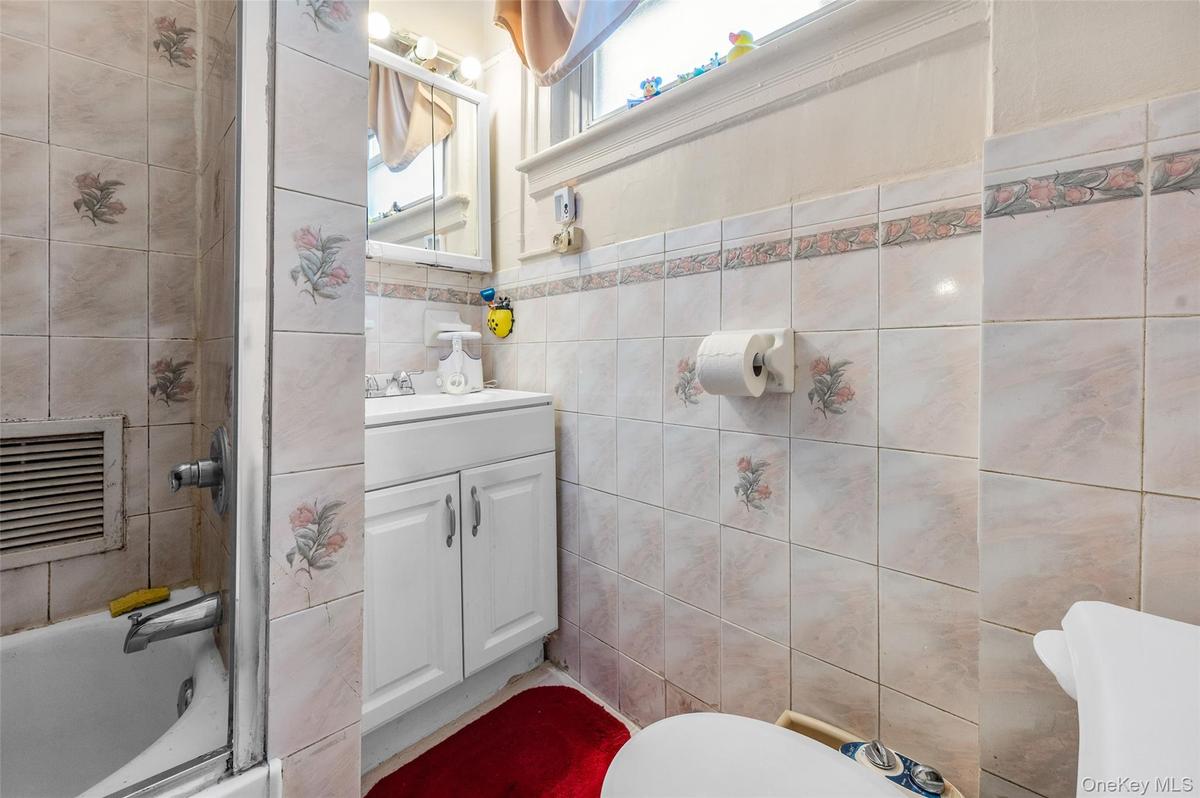 Full bathroom with vanity, tile walls, and tub / shower combination