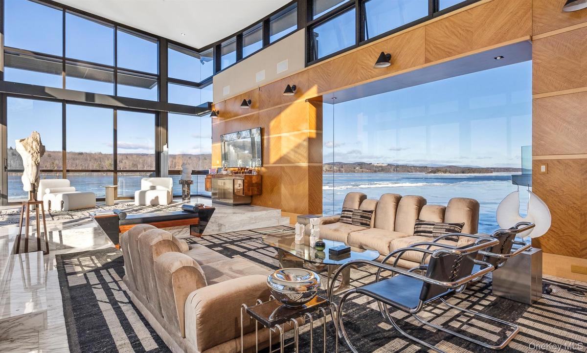 Living room featuring wood walls, a water view, and a high ceiling