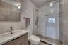 Full bathroom with toilet, vanity, tile walls, a shower stall, and tasteful backsplash