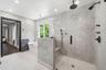 Spacious bathroom featuring a frameless glass shower enclosure, matte black fixtures, and a built-in shower bench