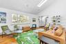 Living room with baseboard heating, high vaulted ceiling, a skylight, and hardwood / wood-style floors