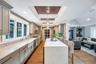 Spacious kitchen featuring an expansive island with seating, a farmhouse sink, stainless steel appliances, and gray cabinetry