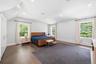 Spacious room featuring rich wood-finish flooring, white walls, and a vaulted ceiling with recessed lighting