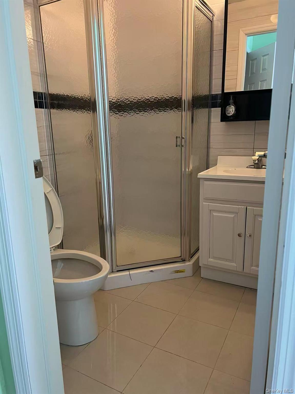 Full bathroom featuring vanity, tile patterned floors, a stall shower, and toilet