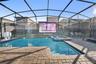 Private screen enclosed pool and hot tub with projector screen, outdoor dining, and lounge area.