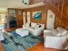 Living room featuring wood walls, wood finished floors, a ceiling fan, and a brick fireplace