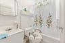 Bathroom with toilet, shower / bathtub combination with curtain, tile walls, and vanity