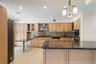 Kitchen featuring an expansive island with a dark stone countertop, light wood cabinetry, recessed lighting, and tile flooring