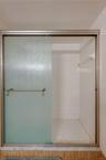 Close-up view of the primary suite’s shower showcases a hexagon tile floor and full tile surround behind frosted sliding doors.
