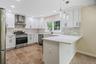 Modern kitchen featuring white shaker cabinetry, stainless steel appliances, light-toned tiled backsplash, and recessed lighting