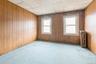 Empty room with a paneled ceiling, radiator, carpet flooring, and wooden walls