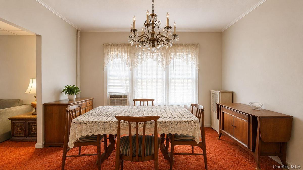 Dining area featuring a crystal chandelier, crown molding, and an accent wall