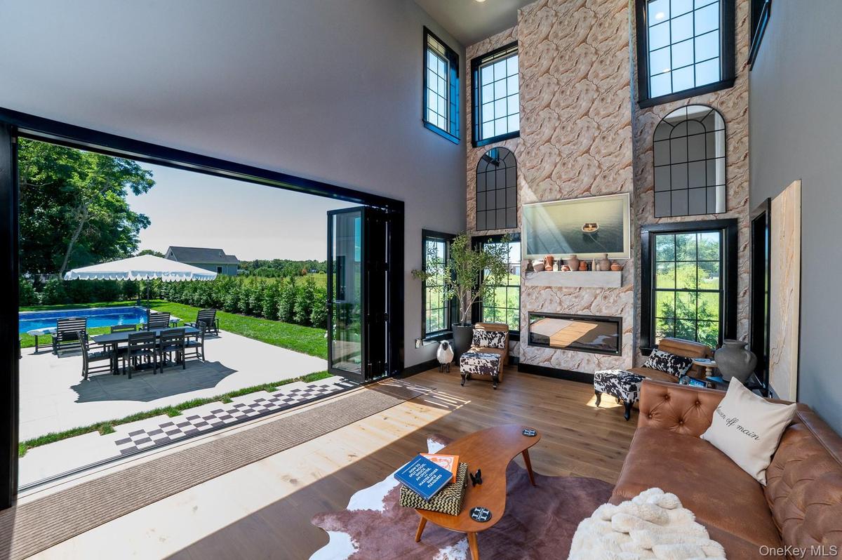 Furnished living room with a fireplace, wood finished floors, and a high ceiling