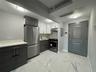 Kitchen with modern cabinets, stainless steel appliances, white cabinets, and light marble finish flooring
