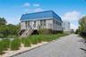 View of front of house featuring a standing seam roof, driveway, stairway, and metal roof