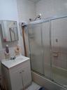 Bathroom featuring combined bath / shower with glass door, vanity, tile walls, and light tile patterned flooring
