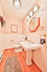 Half bath featuring a wainscoted wall, light wood-type flooring, and a baseboard heating unit