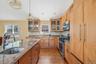 Kitchen with light wood-style floors, appliances with stainless steel finishes, glass insert cabinets, light stone countertops, and decorative light f