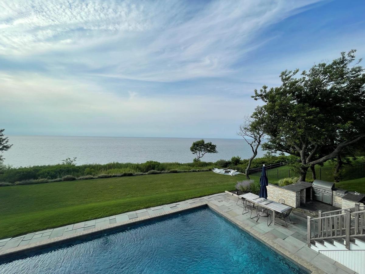 View of swimming pool with a lawn, a water view, a patio, and an outdoor kitchen