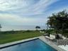 View of swimming pool with a lawn, a water view, a patio, and an outdoor kitchen