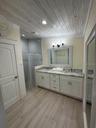 Master bathroom features timeless fixtures, a separate toliet room, a large vanity with double sinks, and a spacious walk-in shower. Soft lighting and