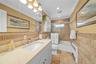 Full bathroom featuring tile walls, vanity, bath / shower combo with glass door, radiator, and ornamental molding